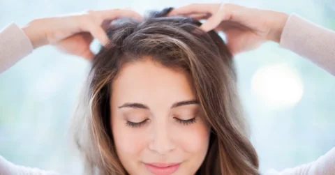 Woman gently massaging her healthy scalp, smiling
